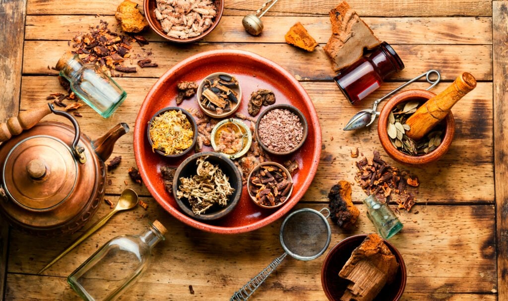 Image of a wooden table filled with herbs to represent the meaning of adaptogen and its many forms.