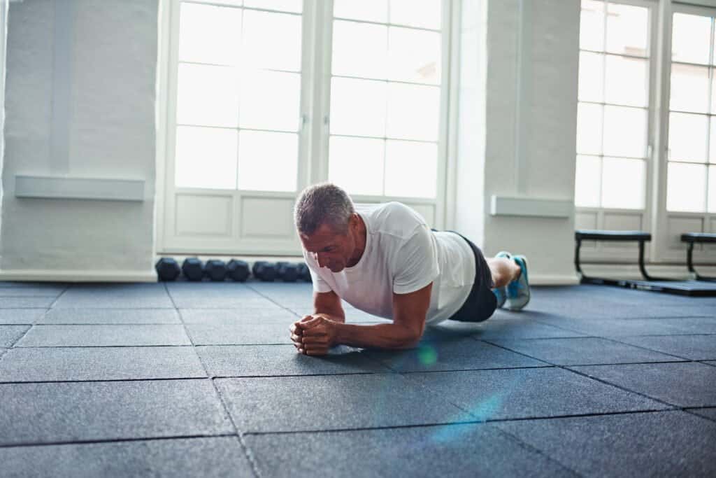 As we age and looking for every edge we can get while we workout, we wonder can zinc increase testosterone. As older man completes a plank with ease on gym mats.