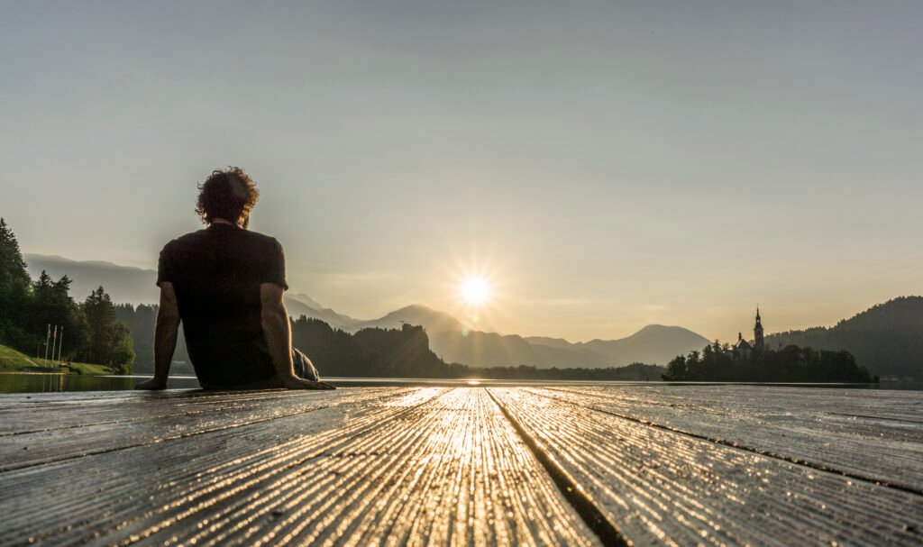 Man sitting on edge of a deck enjoying a sunrise peacefully - Is Tongkat Ali his key to enjoying this moment?