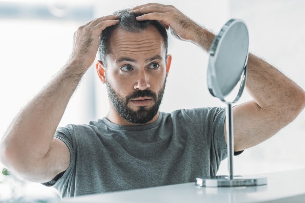 Man noticing his thinning hair in the mirror - could a natural solution like Saw Palmetto help?