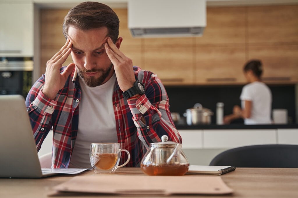 Man stressed in kitchen with hands to his head - could Maca Root be his answer to a more stress free life?