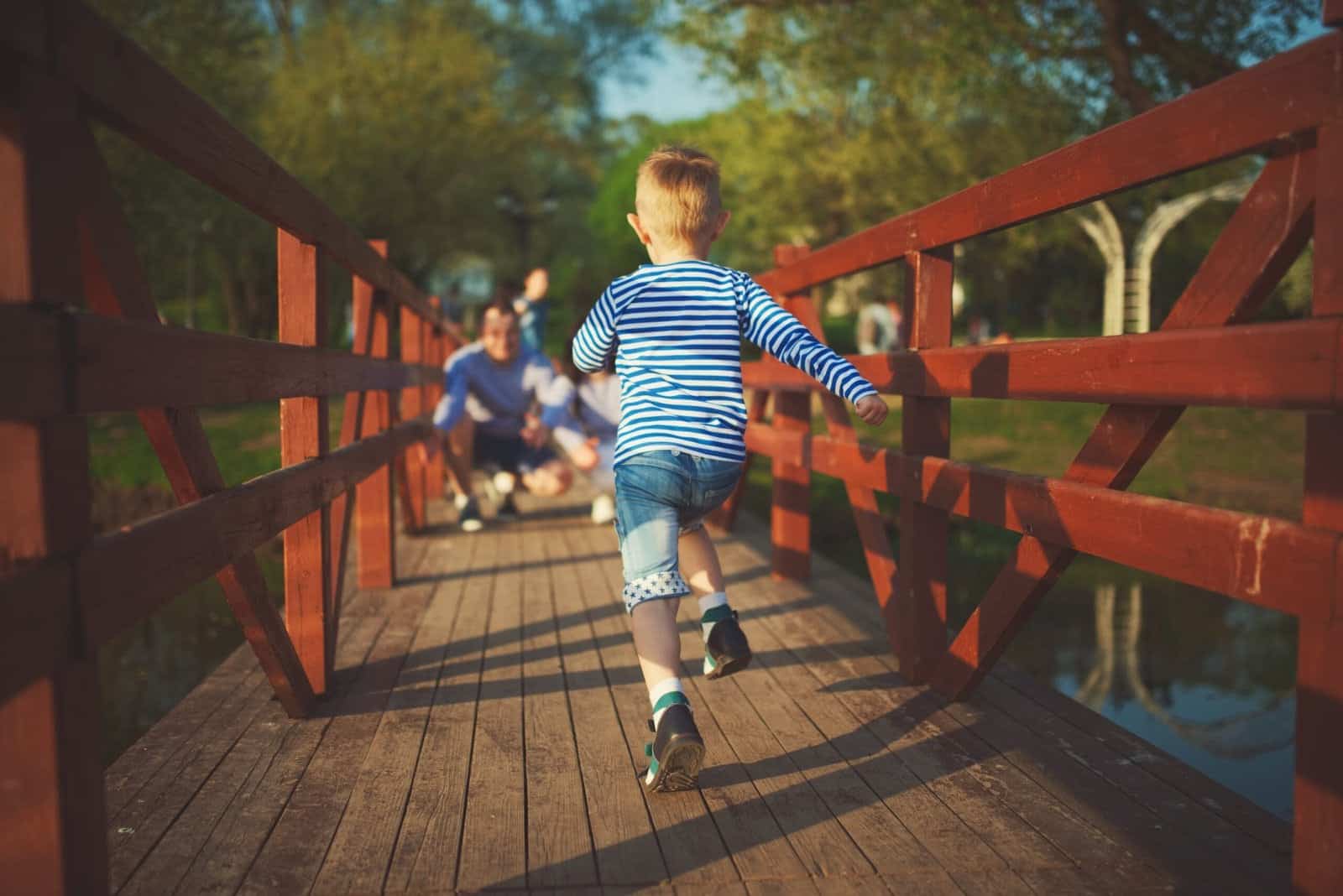 Little Boy Running over a bridge towards his father and siblings