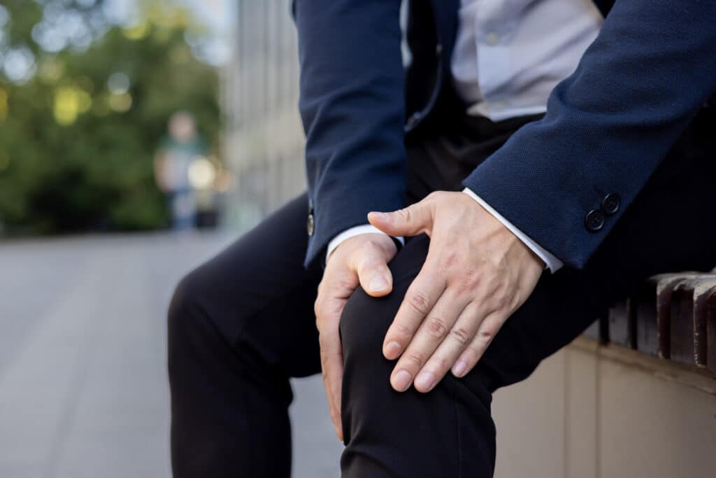 man grabbing his sore knee with two hands. Could supplementing with chamomile reduce chronic inflammation?