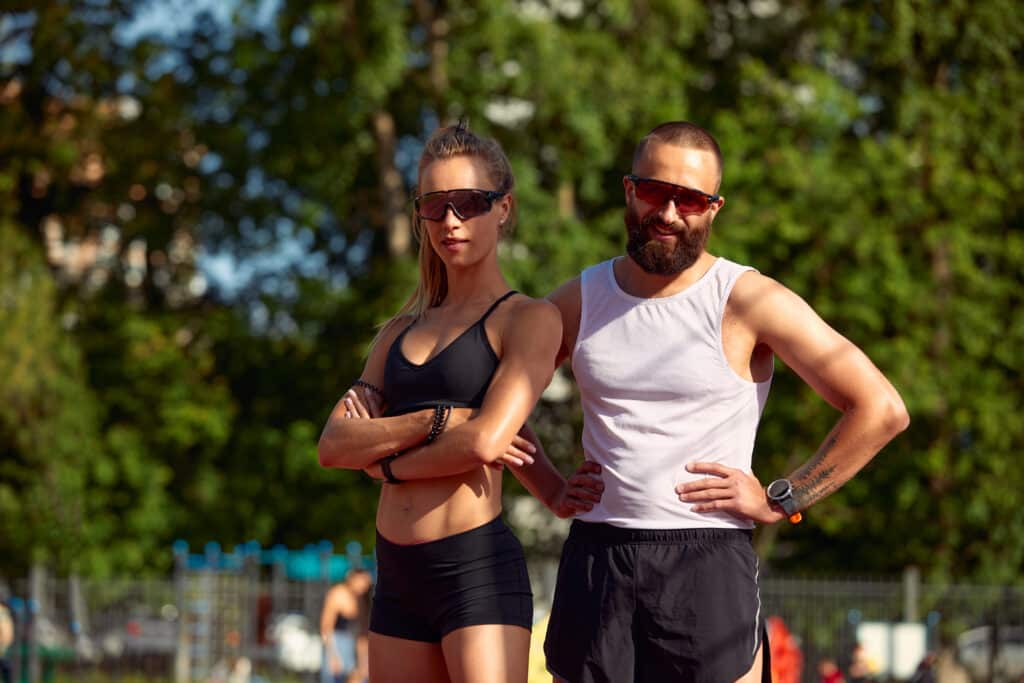 athletic man and woman with gym clothes outside in park on a sunny day. Man is taking on shwagandha vs Tongkat Ali for Boosting Male Libido