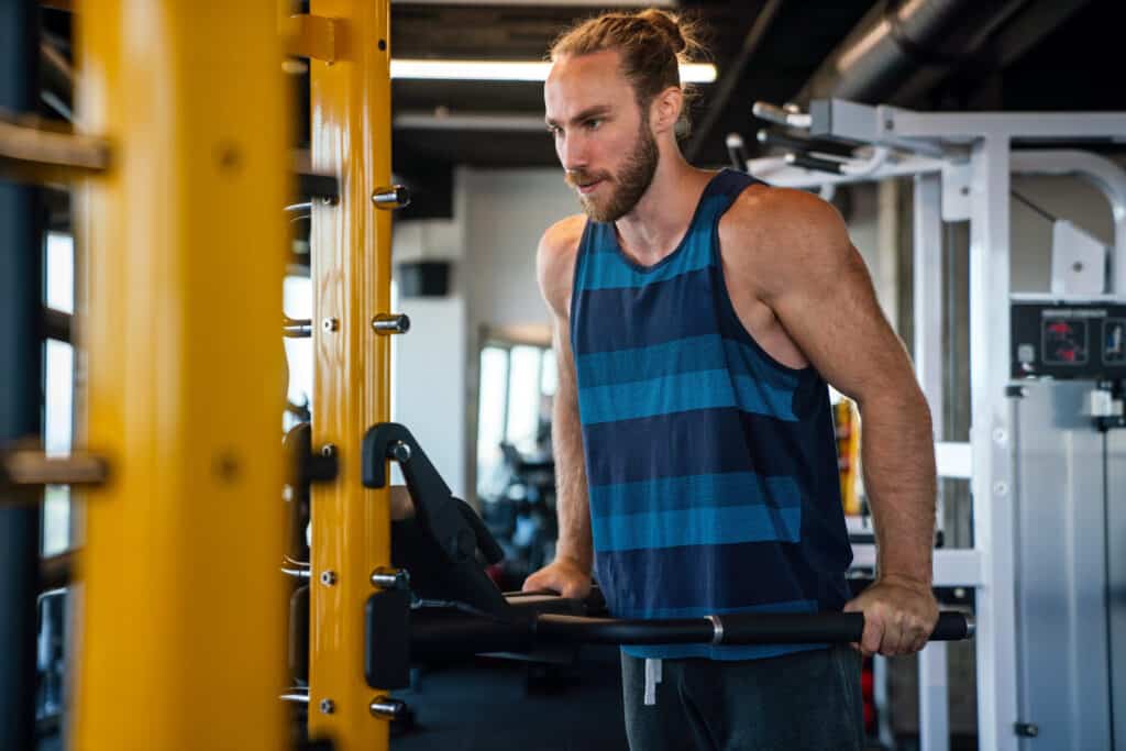 Muscular man working out in gym doing exercises to stay healthy deciding between Maca vs Ashwagandha