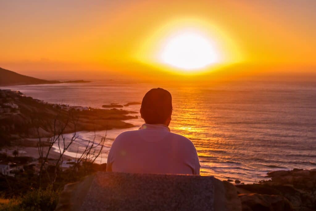 a person sitting on a rock looking at the sunset wondering about ashwagandha vs magnesium