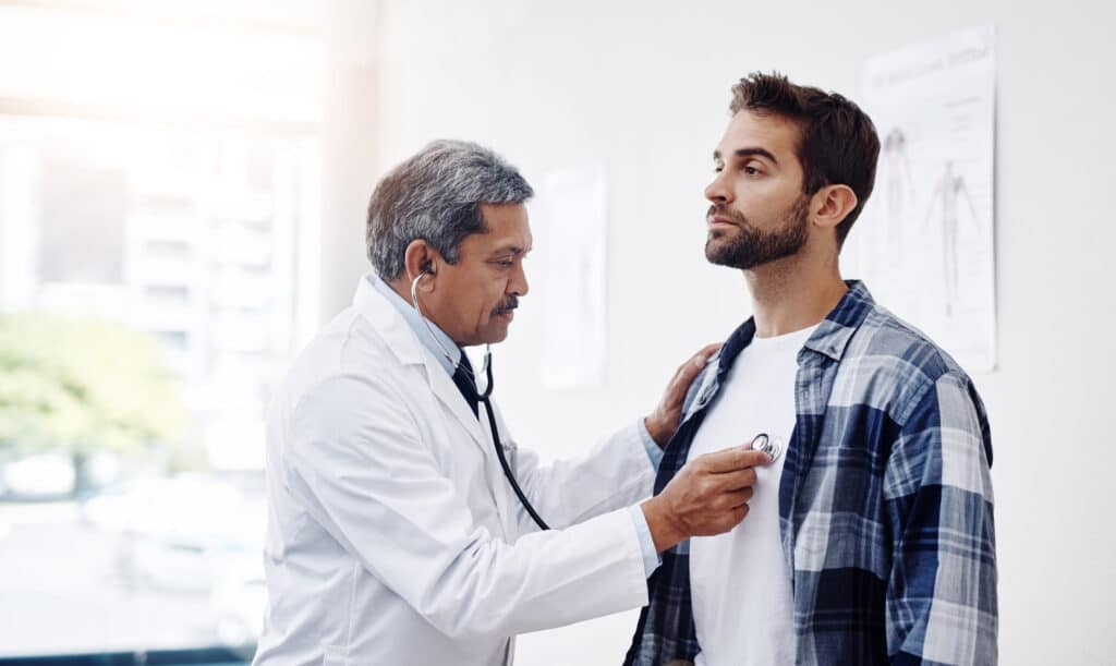 a doctor examining a man's chest to discuss how to lower ApoB and health lifestyles