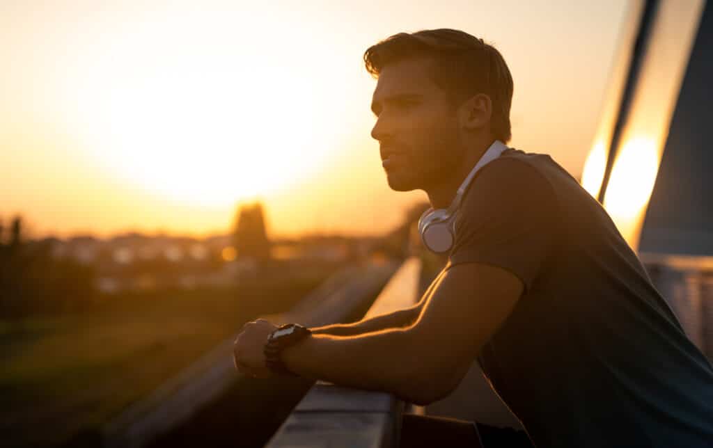 a man leaning on a railing with headphones on wondering which supplements to reduce anxiety