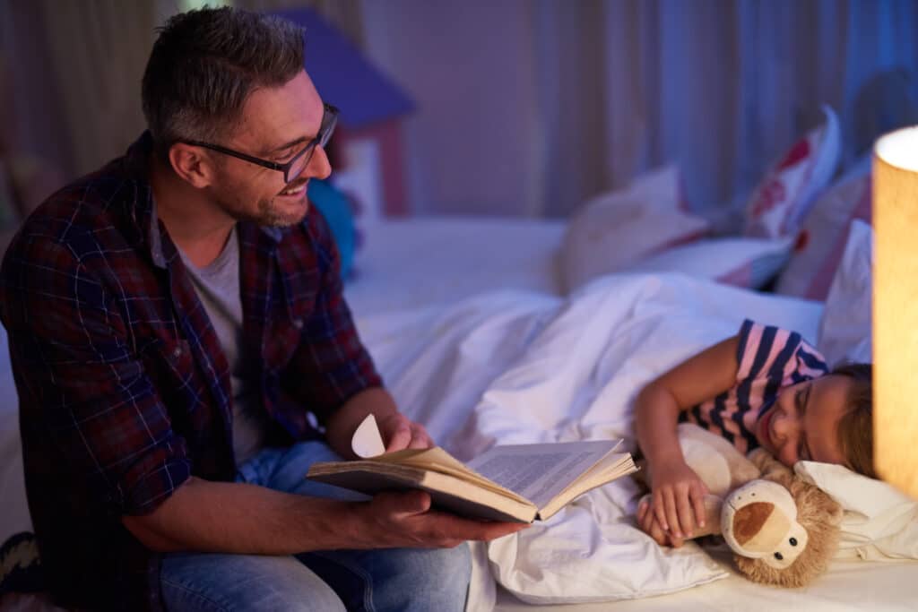 a man reading a book to a child after taking ashwagandha supplements for better sleep