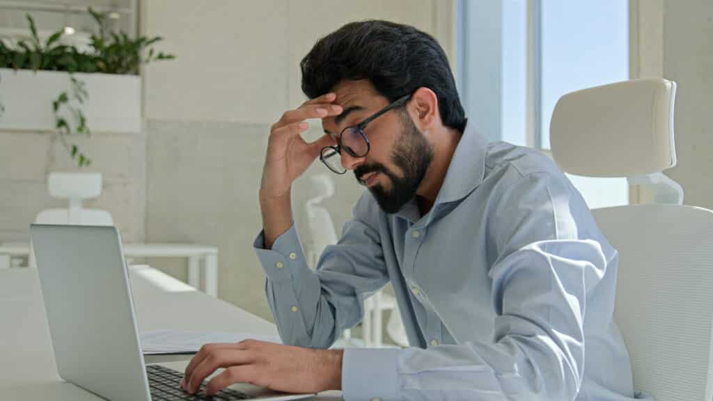 A man with a beard and glasses stressed work thinking he should have supplements for better sleep.