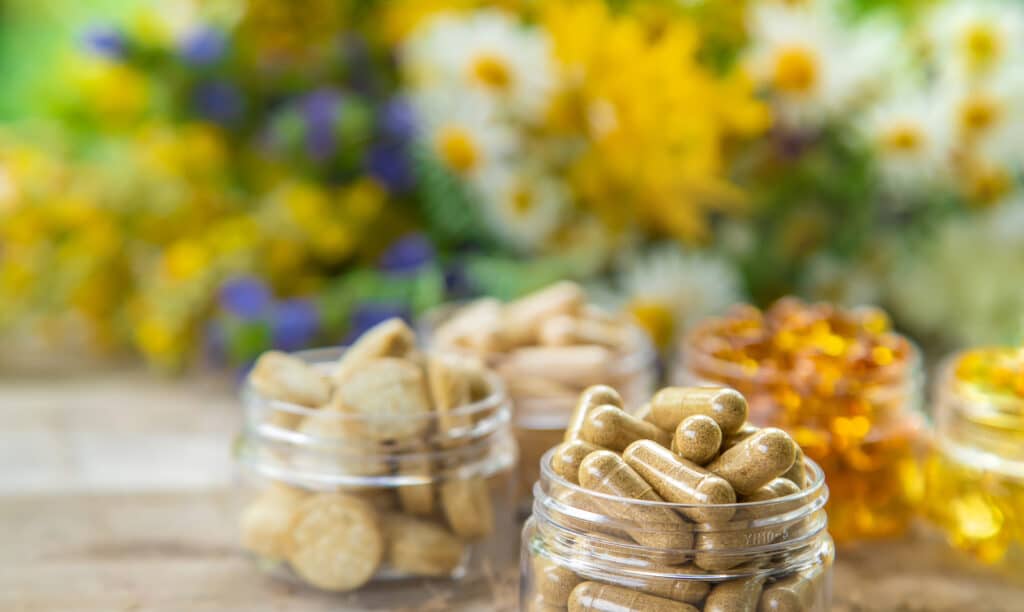 a group of glass jars filled with different types of homeopathic pills to approach Ashwagandha vs Rhodiola for Calming Support.