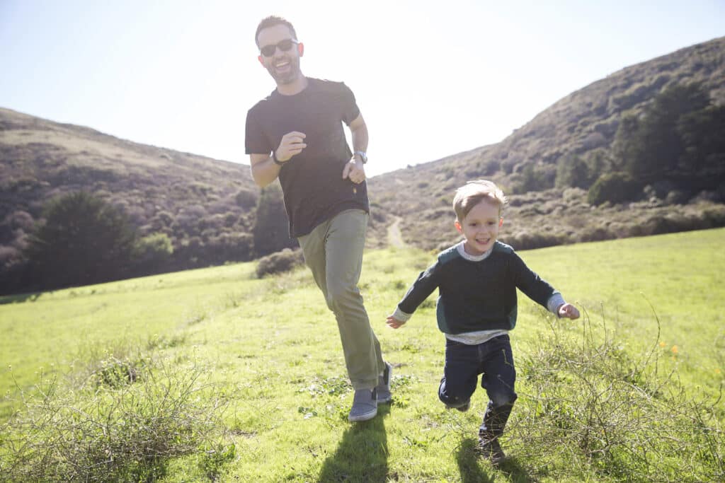 Young father and son running in a field as he supplements with Niagen Benefts.