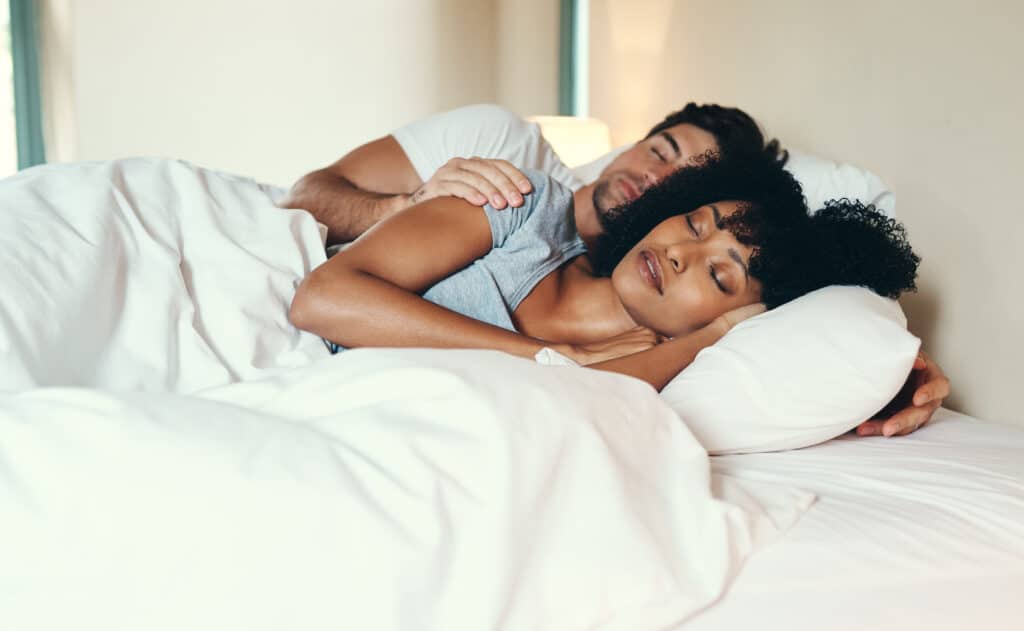 A couple embracing on their sides asleep in bed - is it from Melatonin or Valerian Root that accounts for this great sleep?