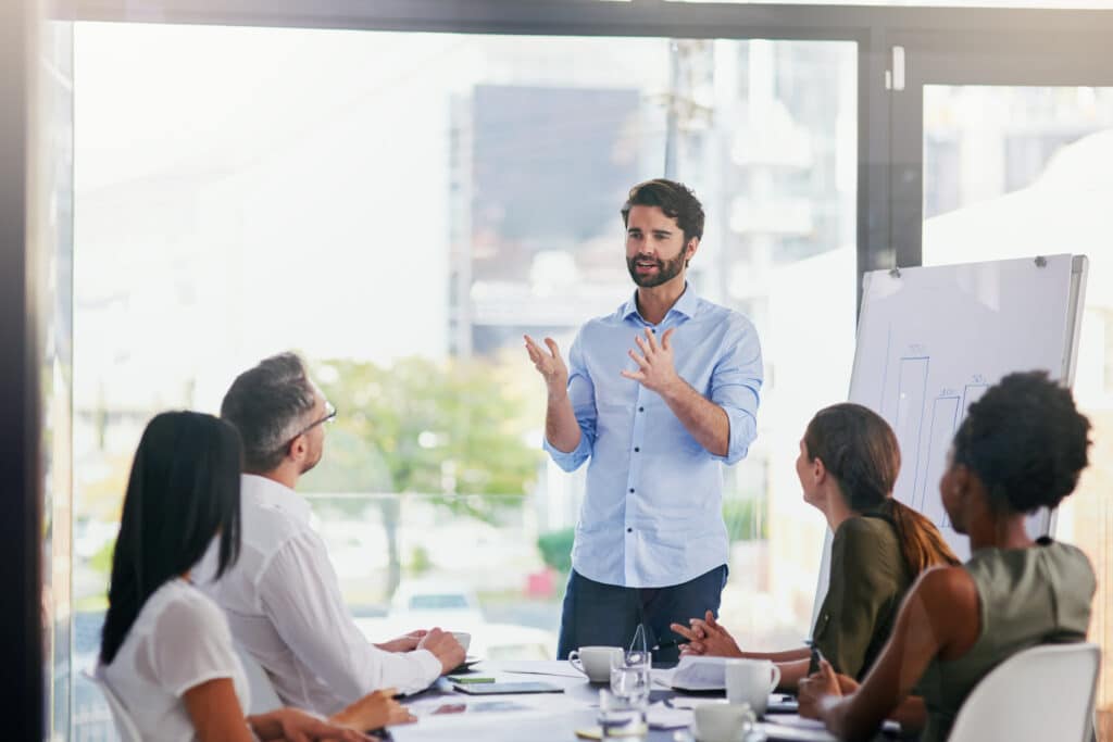 Man in blue shirt in office meeting presenting to others with high spirits due to adaptogens and nootropics